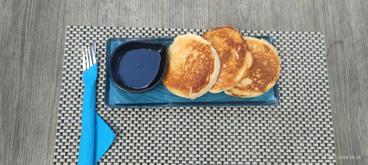 Pancakes dorés avec sirop d'érable sur assiette céramique bleue